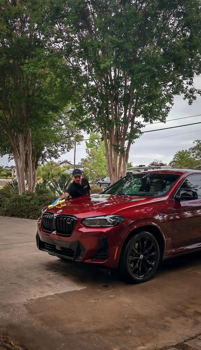 Joji's Mobile Detailing technician wiping down a red BMW