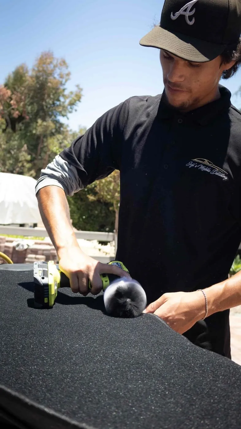 Paint correction in progress, technician machine-polishing a vehicle in San Diego
