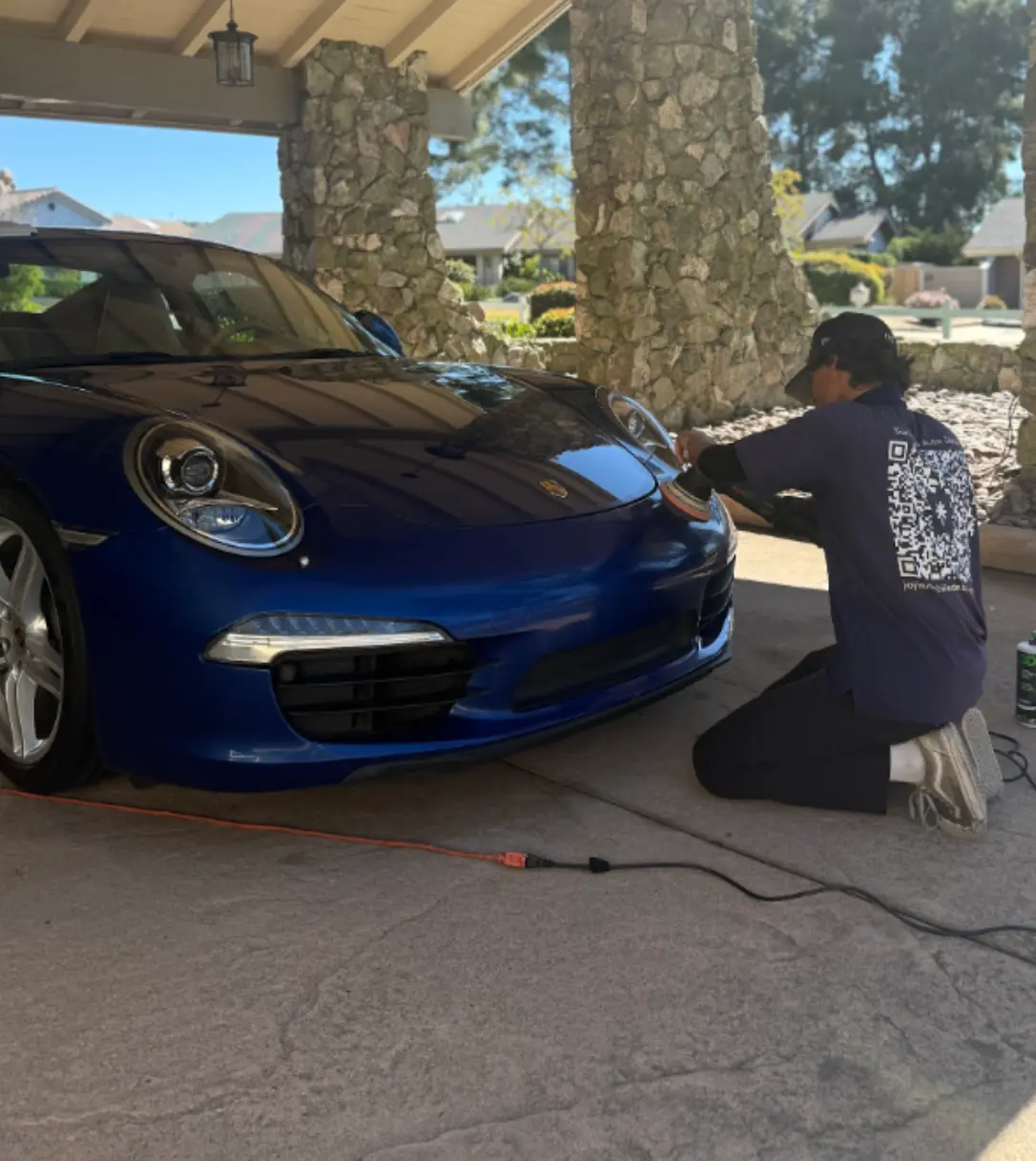 National City paint correction: technician machine-polishing the front bumper of a blue Porsche 911